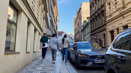 Three people walking along a cobblestone street and looking at historic buildings