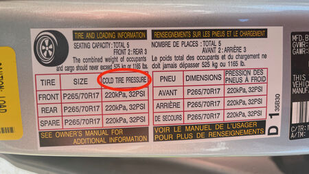Label on vehicle door frame showing tire size and proper pressure to inflate tires.